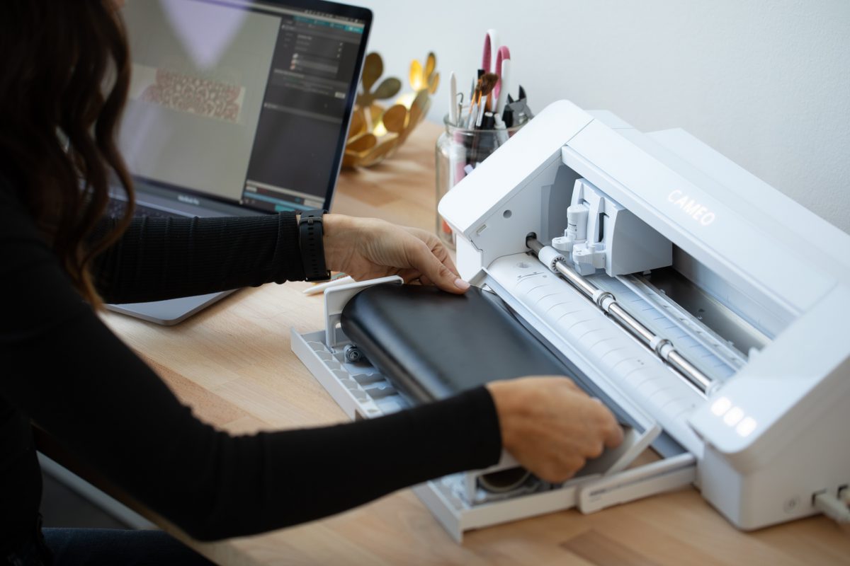 femme utilise un plotter de decoupe blanc_elle mets une femme de flex dans la machine